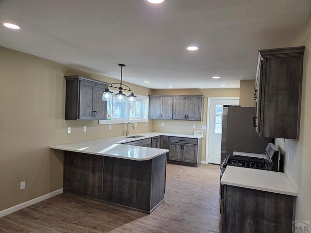 kitchen with range with gas cooktop, a sink, a peninsula, and wood finished floors