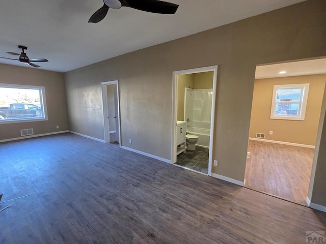 unfurnished bedroom with baseboards, visible vents, multiple windows, and wood finished floors