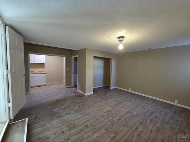 spare room featuring dark wood-style floors, baseboards, and a textured ceiling