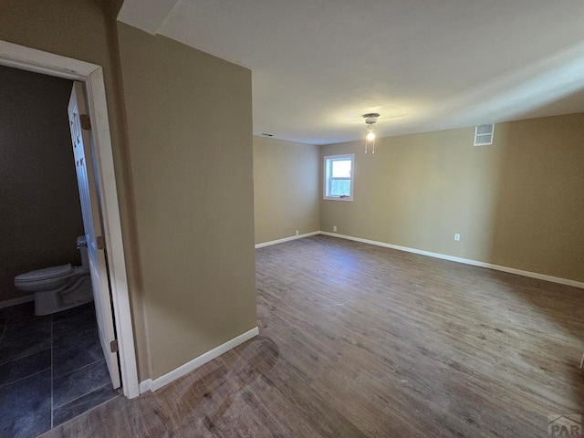 spare room featuring visible vents, baseboards, and wood finished floors