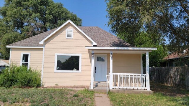 bungalow-style home with a shingled roof, fence, and a porch