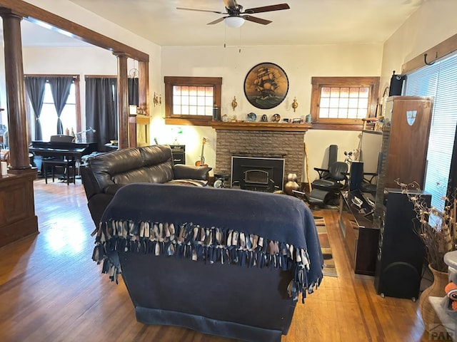 living room featuring a ceiling fan, decorative columns, and wood finished floors
