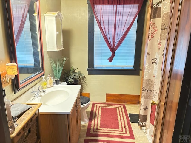 bathroom with toilet, vanity, and a healthy amount of sunlight