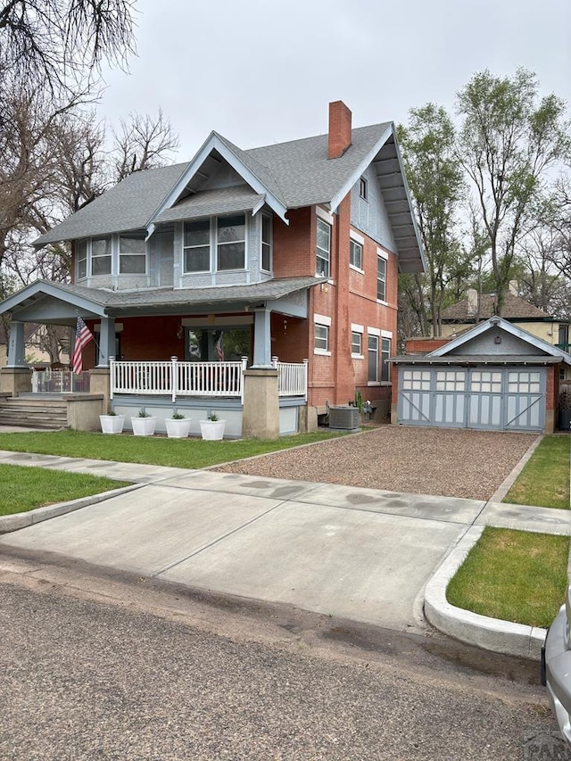 view of front of house featuring a porch, a garage, a shingled roof, an outbuilding, and a chimney
