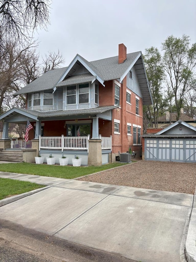 view of front of house with a chimney, covered porch, an outbuilding, central air condition unit, and driveway