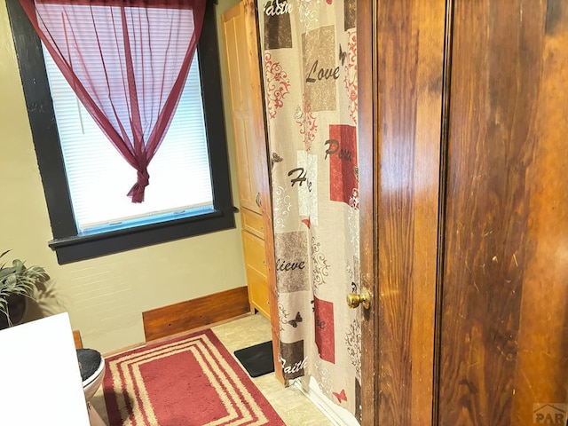 full bathroom with toilet, a shower with curtain, and baseboards