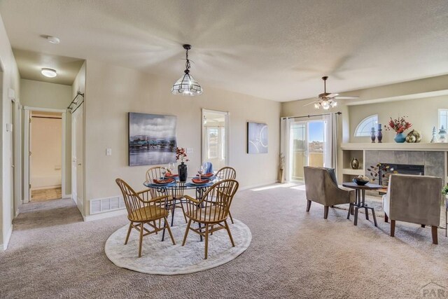 1447 Madison Ridge Hts Unit E, Colorado Springs, CO 80904 - dining room with carpet flooring, a textured ceiling, a tiled fireplace, and a ceiling fan