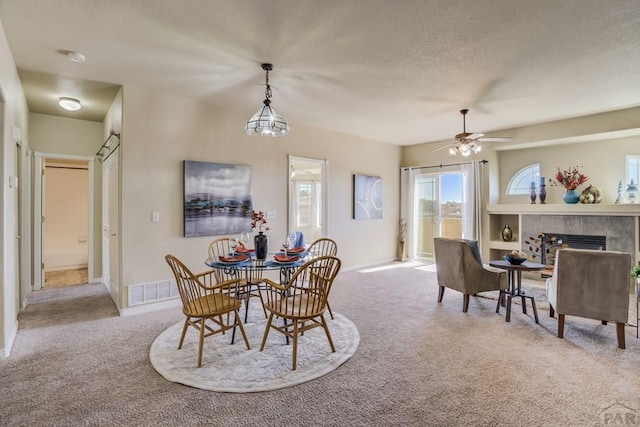 1447 Madison Ridge Hts Unit E, Colorado Springs, CO 80904 - carpeted dining space featuring a fireplace, a ceiling fan, a textured ceiling, and baseboards