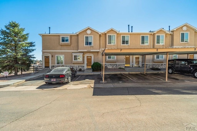 1447 Madison Ridge Hts Unit E, Colorado Springs, CO 80904 - townhome / multi-family property featuring stucco siding, covered parking, and stone siding