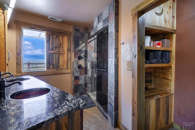 bathroom featuring a shower stall, wood finished floors, and double vanity
