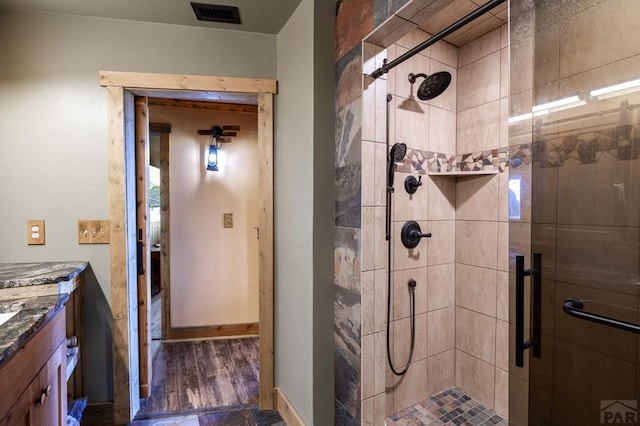 bathroom featuring a shower stall, vanity, baseboards, and wood finished floors