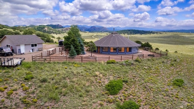 rear view of house with an exterior structure, an enclosed riding area, an outbuilding, a view of rural / pastoral area, and a mountain view