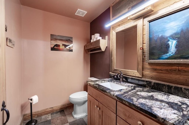 half bathroom featuring toilet, baseboards, and vanity