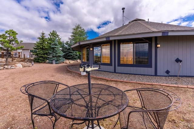 rear view of property featuring a shingled roof and a patio area