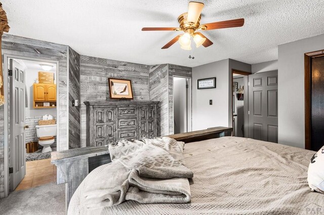 bedroom with a textured ceiling, ceiling fan, light tile patterned floors, and ensuite bathroom