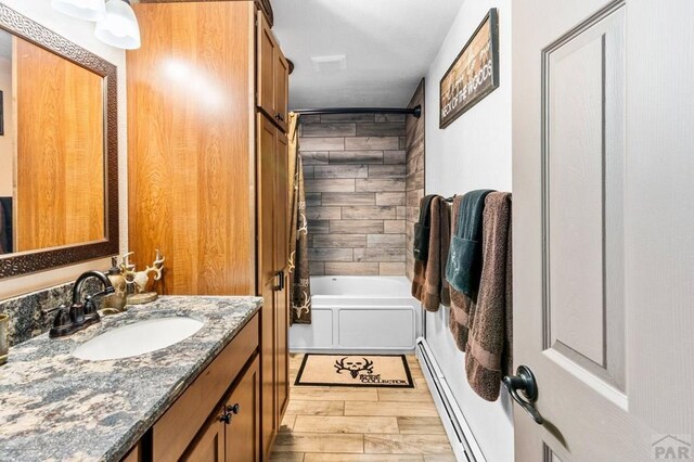 full bathroom featuring wood finish floors, baseboard heating, shower / bath combination, and vanity