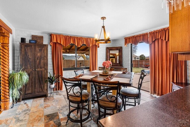 dining room with stone finish floor and a notable chandelier