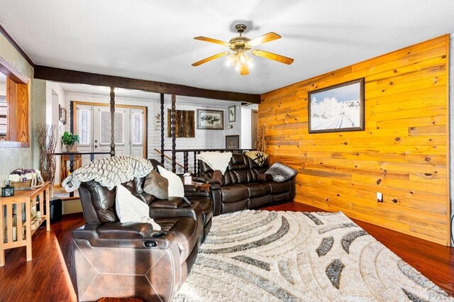 living room featuring dark wood-type flooring, wood walls, and a ceiling fan