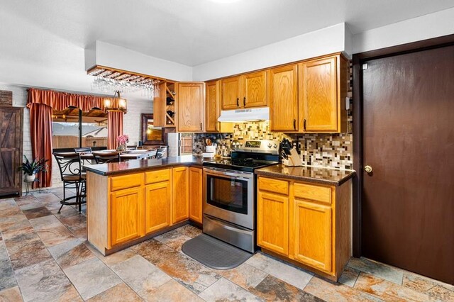 kitchen with dark countertops, electric range, a peninsula, and under cabinet range hood