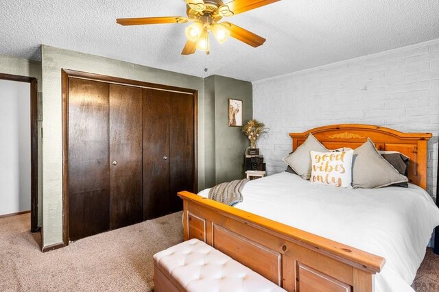 carpeted bedroom with ceiling fan, a textured ceiling, and a closet