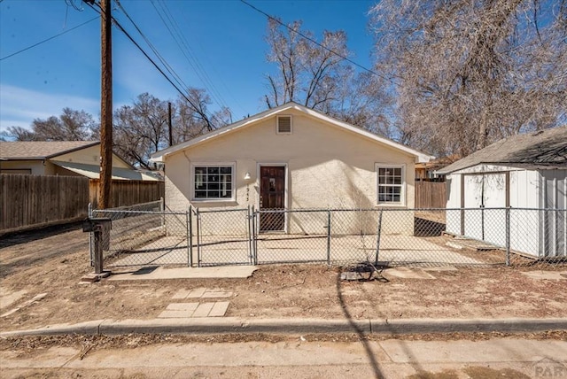 bungalow featuring an outbuilding, fence private yard, a shed, and stucco siding