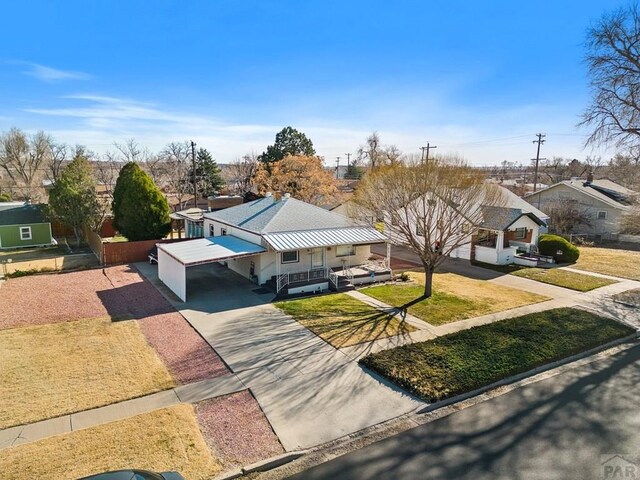 view of front facade with concrete driveway, a residential view, a front lawn, a porch, and a carport