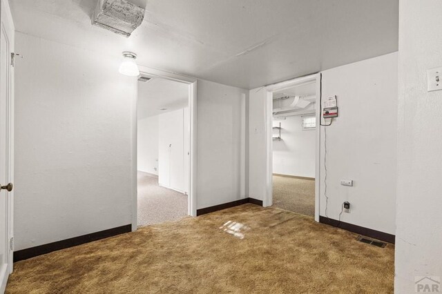 unfurnished room with baseboards, visible vents, and dark colored carpet