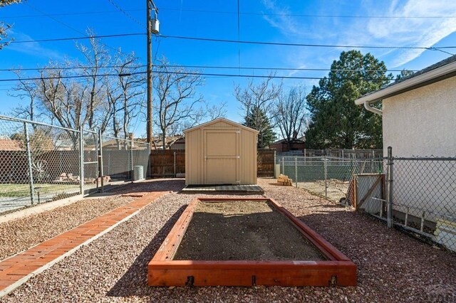 view of yard featuring a storage shed, an outbuilding, a fenced backyard, and a garden