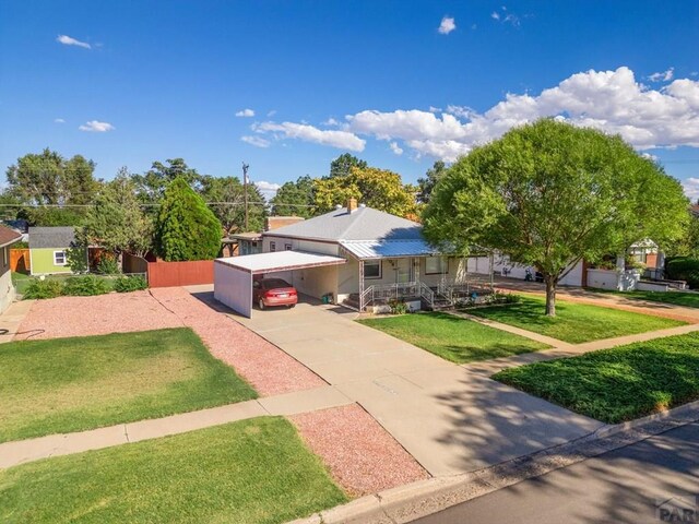 ranch-style house featuring driveway, fence, a front lawn, and a carport