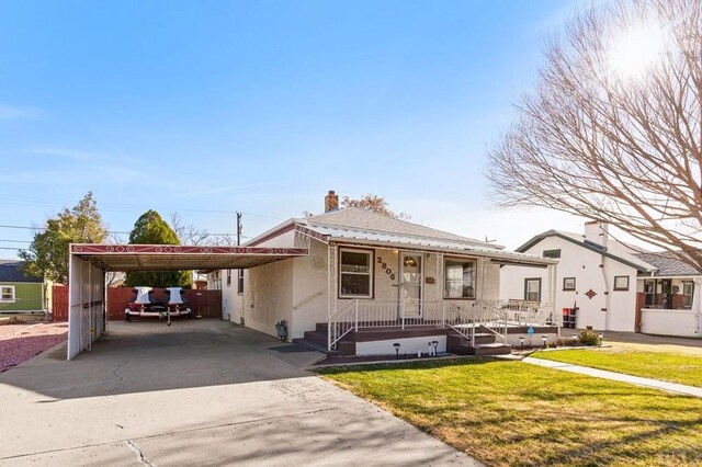 view of front of house with a carport, a front yard, driveway, and stucco siding