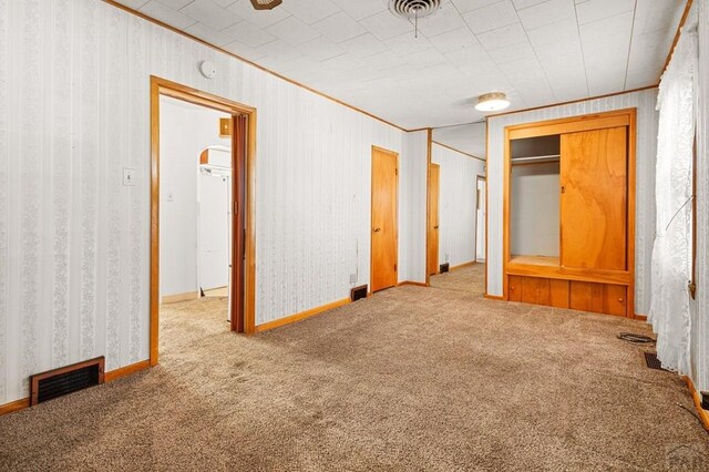 unfurnished bedroom featuring ornamental molding, carpet flooring, and visible vents