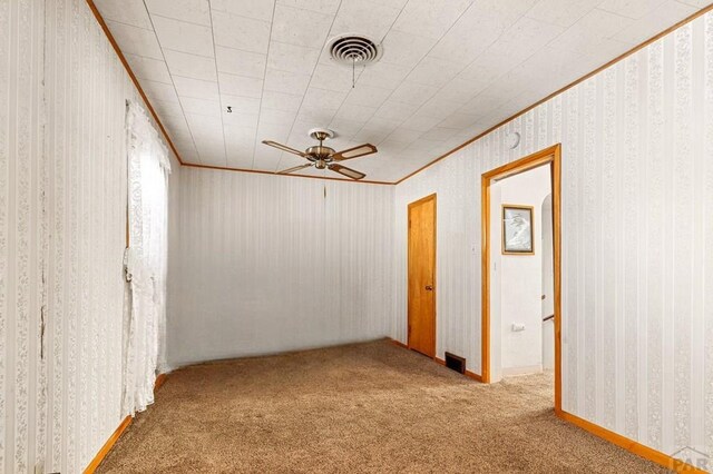 unfurnished room featuring light carpet, wallpapered walls, visible vents, a ceiling fan, and ornamental molding