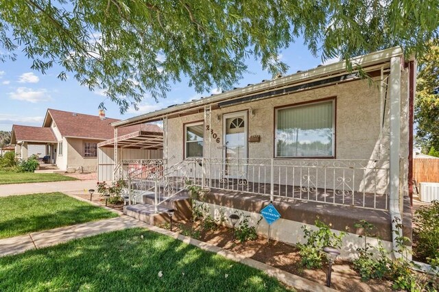 view of front of property with a porch, a front lawn, and stucco siding