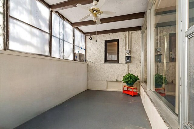 unfurnished sunroom featuring a ceiling fan and beam ceiling