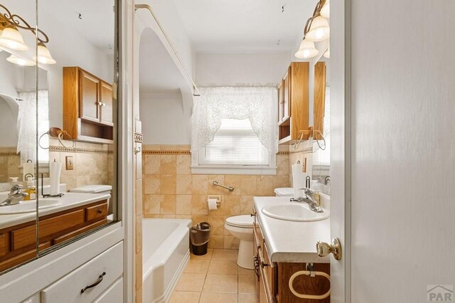 bathroom with tile walls, tile patterned floors, toilet, vanity, and a bath