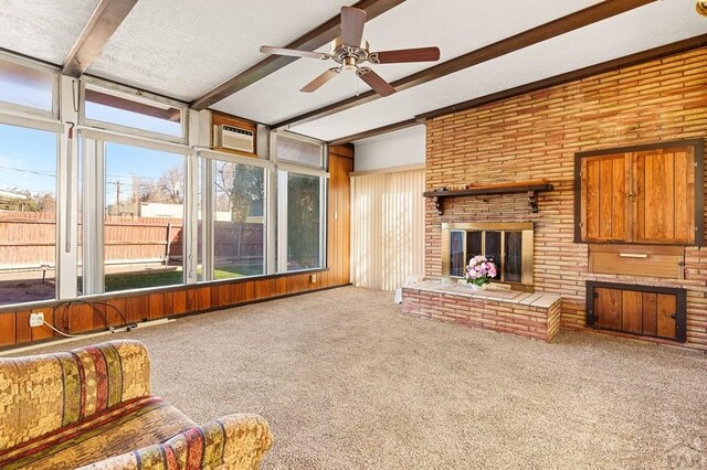 carpeted living room with a fireplace, a ceiling fan, beam ceiling, and a wall mounted air conditioner