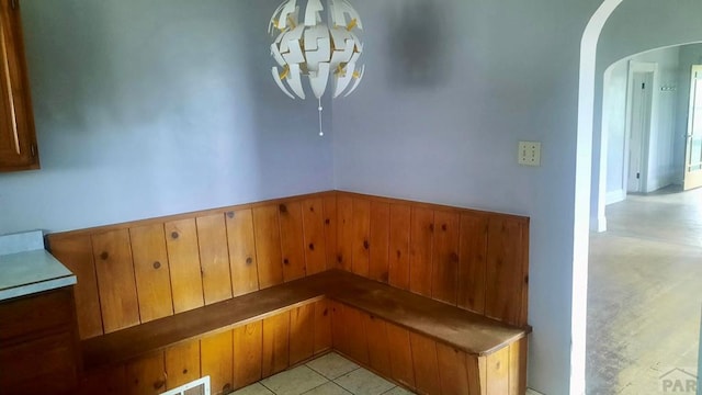 205 Tyler St, Walsenburg, CO 81089 - unfurnished dining area with arched walkways, a wainscoted wall, a chandelier, and wood walls