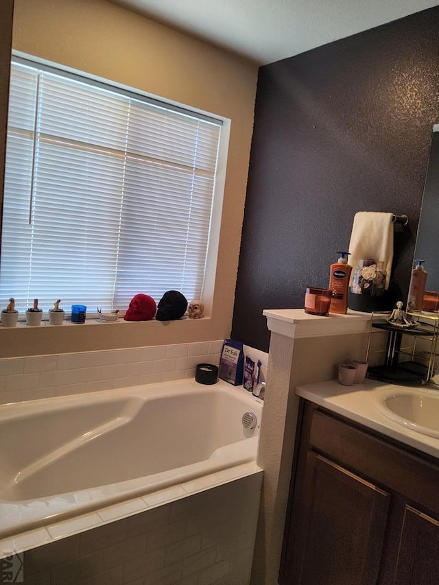 bathroom featuring a textured wall, a garden tub, and vanity