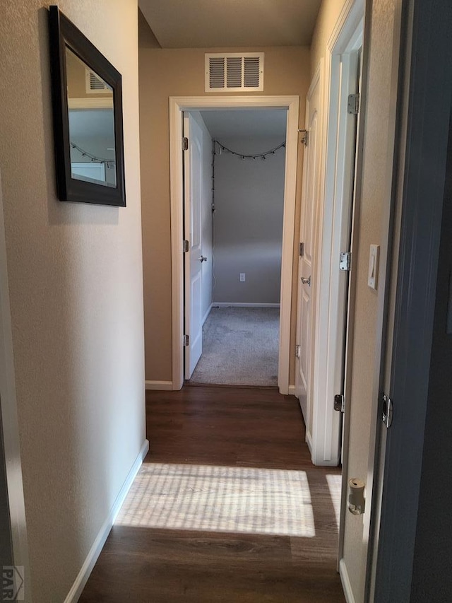 hallway with visible vents, baseboards, and wood finished floors