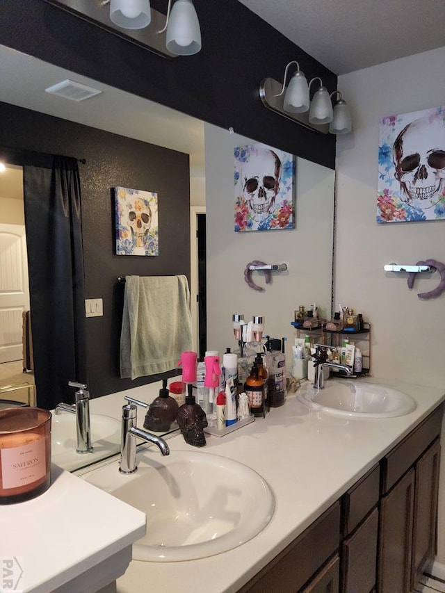 bathroom featuring visible vents, a sink, and double vanity