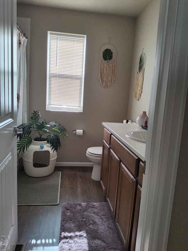 full bath with toilet, wood finished floors, vanity, and baseboards