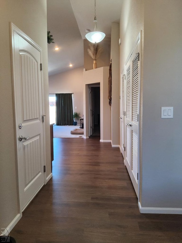 hallway with dark wood-style floors, lofted ceiling, and baseboards