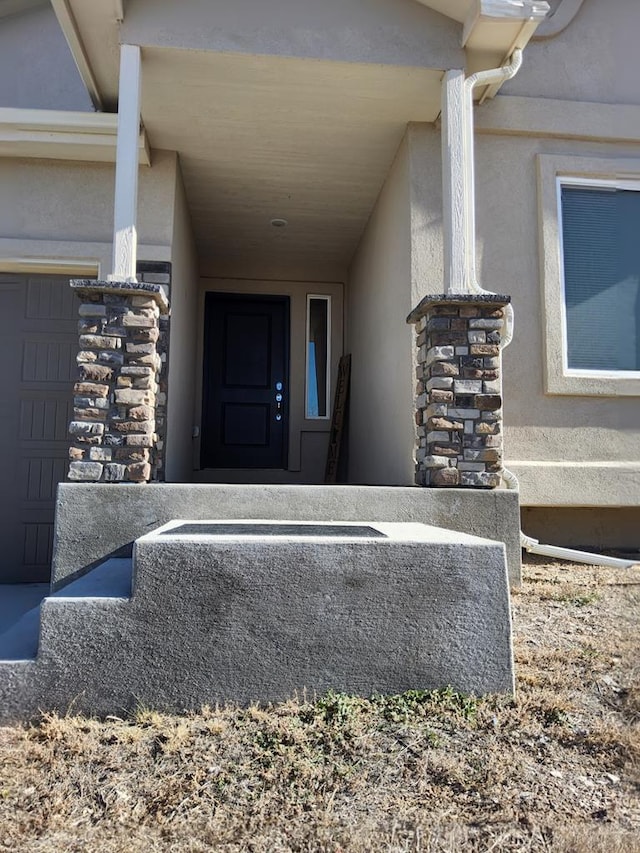 view of exterior entry with a garage and stucco siding