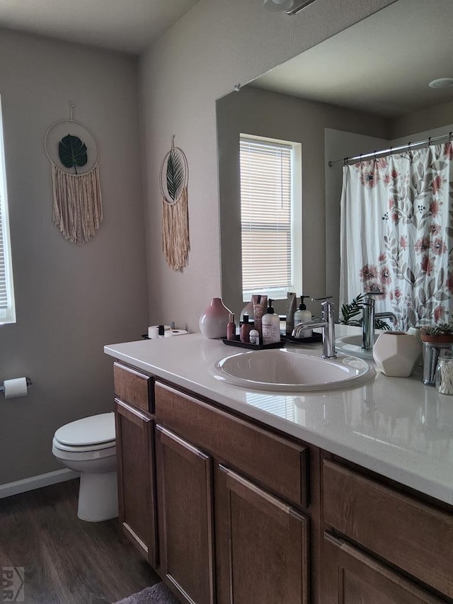 full bath with baseboards, vanity, toilet, and wood finished floors