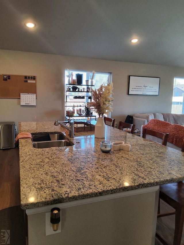 kitchen featuring dark wood-style flooring, recessed lighting, a sink, and a kitchen breakfast bar