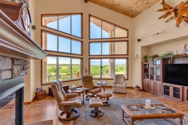 living area with wooden ceiling, light wood-style flooring, a fireplace, and high vaulted ceiling