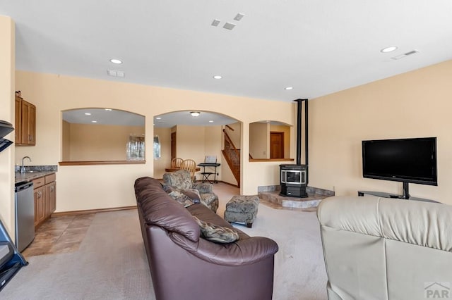 living room with recessed lighting, a wood stove, visible vents, and stairway