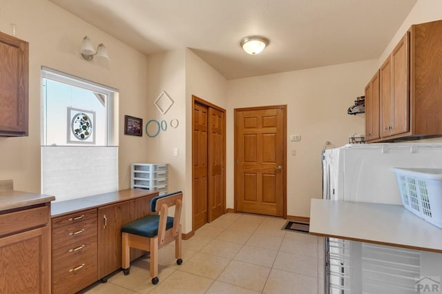 kitchen with light tile patterned floors, light countertops, brown cabinetry, and baseboards