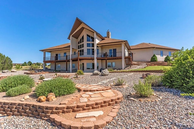 rear view of property with a deck, a chimney, and stucco siding