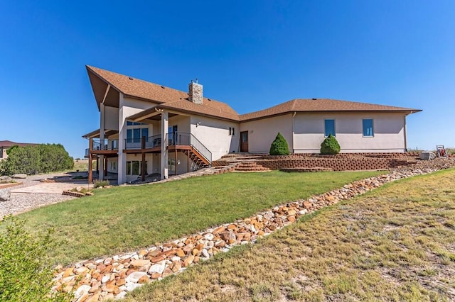 view of front facade featuring a front yard, stucco siding, a chimney, and stairs